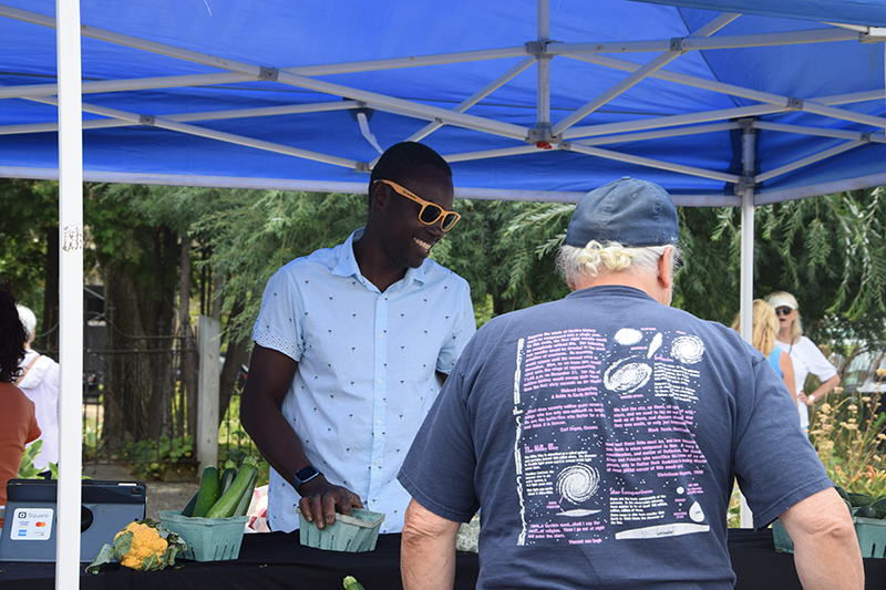 Kafui Okai Adjei, or K.K., smiles during an interaction with a customer during the Harbor Springs Farmers Market on Wednesday, Aug. 9.