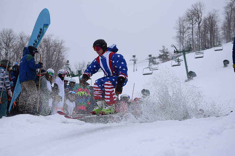 A skier is splashed by water after exiting ‘Lake Nubs’ during the Mardi Gras event March 18 at Nub’s Nob.